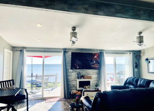 Cozy living room with a view of the water, featuring a TV, seating area, and sliding glass doors to an outdoor patio.