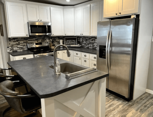 Modern kitchen with white cabinets, stainless steel appliances, a gray countertop, and a central island with seating.