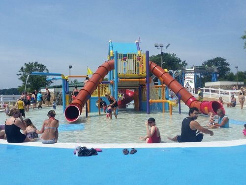A colorful water park with slides, children playing in the water, and families relaxing around the pool area.