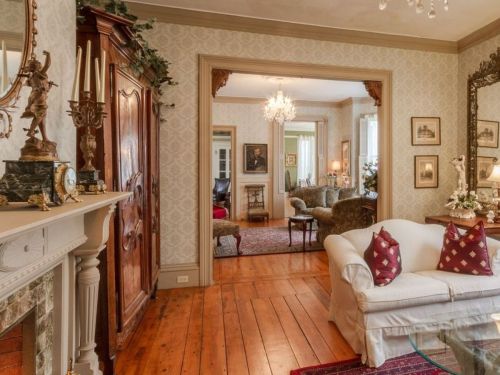 Cozy living room with a white sofa, decorative pillows, wooden floors, and elegant furnishings in a warm, inviting setting.