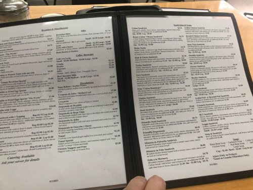 A menu open to two pages, featuring various food items and prices, including sandwiches and breakfast options.