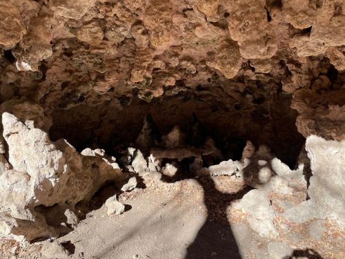 A rocky cave interior with uneven surfaces and shadows, showcasing natural formations and textures.