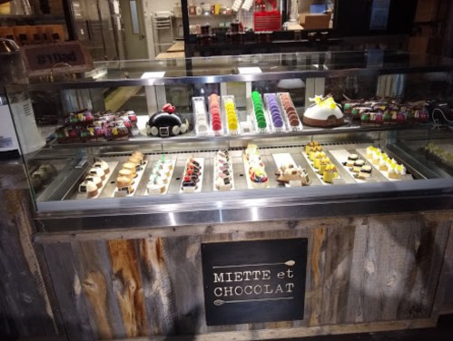 A display case filled with colorful pastries, macarons, and desserts, labeled "Miette et Chocolat."