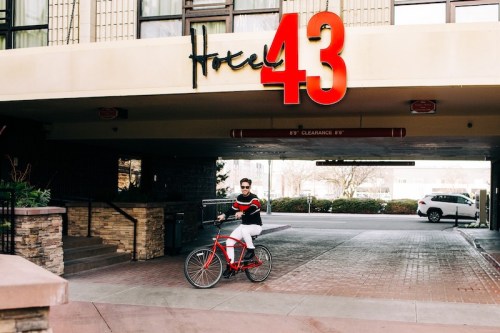A person rides a red bicycle under the sign of Hotel 43, featuring bold red lettering.