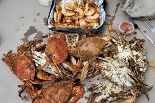 A spread of seasoned crabs and shrimp on a table, with a side of dipping sauce.