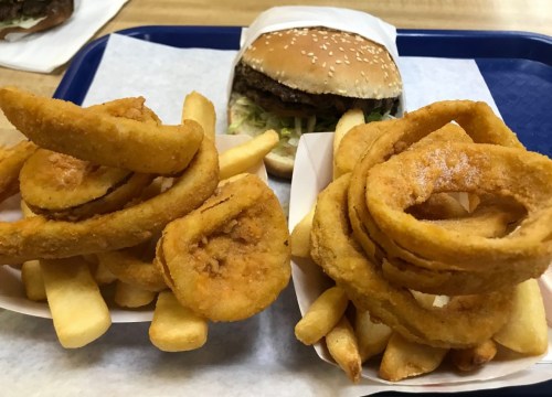 A tray with a burger, fries, and onion rings, showcasing a hearty fast food meal.