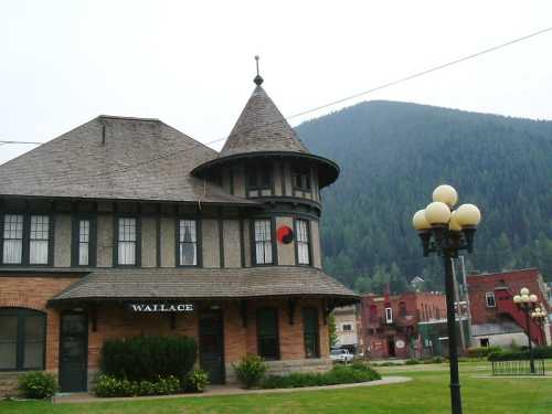 Historic building in Wallace, Idaho, featuring a turret and a sign, with mountains in the background.