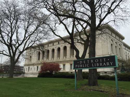 Exterior view of the Detroit Public Library, featuring a grand building and surrounding trees.