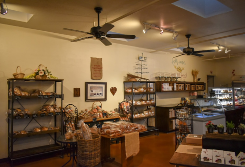 Cozy bakery interior with shelves of bread, pastries, and decor, featuring warm lighting and a welcoming atmosphere.