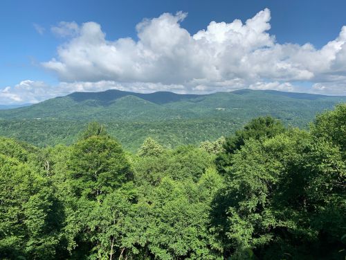 Lush green mountains under a blue sky with fluffy white clouds, showcasing a serene natural landscape.