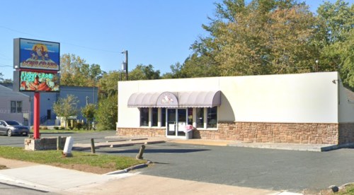 A small restaurant with a sign featuring a cartoon crab, surrounded by trees and a clear blue sky.