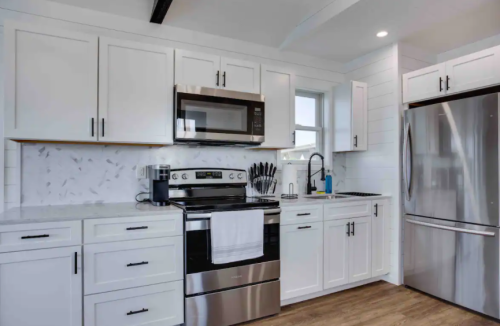 Modern kitchen featuring white cabinets, stainless steel appliances, and a marble backsplash. Bright and spacious design.