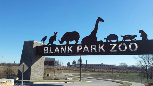 Sign for Blank Park Zoo featuring silhouettes of various animals against a clear blue sky.