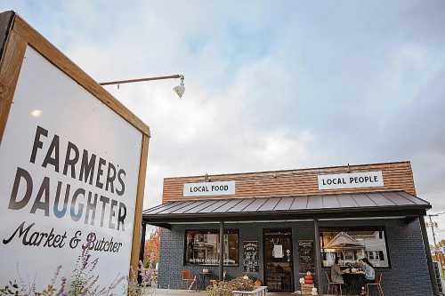 Exterior of "Farmer's Daughter Market & Butcher," featuring a sign and a welcoming storefront with local food emphasis.