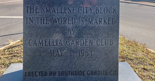 A stone marker reads: "The smallest city block in the world is marked by Camellia Garden Club, May 1, 1964."