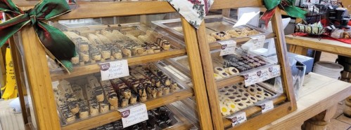 Display case filled with assorted cookies and pastries, decorated with festive ribbons and labels.