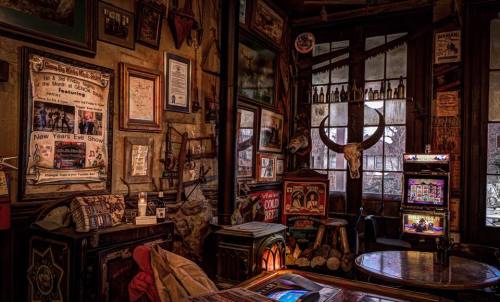 Cozy vintage interior filled with eclectic decor, including posters, a skull, and a retro jukebox. Warm, inviting atmosphere.