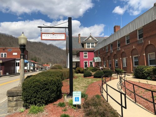 Sign for Glen Ferris Inn in front of a brick building, with landscaped gardens and mountains in the background.