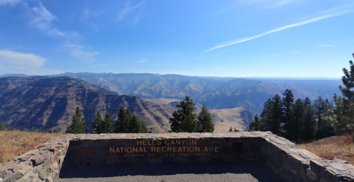View of Hells Canyon National Recreation Area with mountains and trees under a clear blue sky.