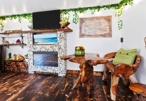 Cozy interior with a stone fireplace, wooden furniture, and greenery accents, creating a warm, inviting atmosphere.