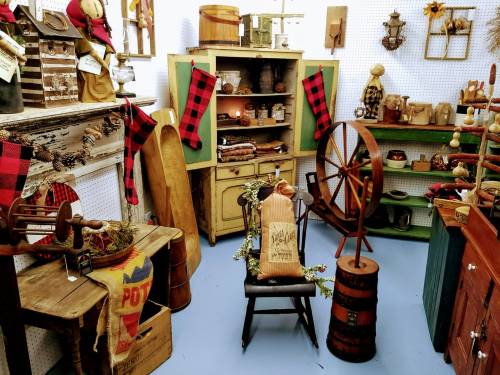 A cozy vintage shop display featuring rustic decor, wooden furniture, and seasonal decorations in warm colors.