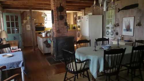 Cozy rustic kitchen and dining area with wooden beams, a stove, and a table set for a meal.