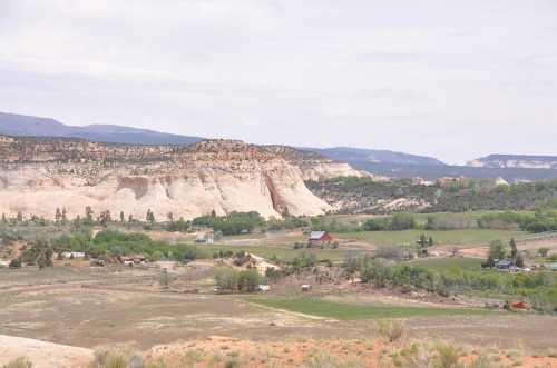 A scenic landscape featuring rolling hills, cliffs, and a small farm with red barns in a green valley.