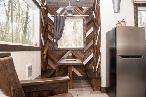 Cozy dining nook with wooden walls, a table, and a fridge, surrounded by large windows and natural light.
