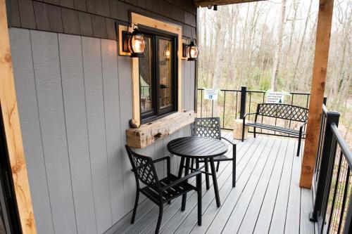 A cozy outdoor patio with a round table and two chairs, surrounded by trees and a railing.