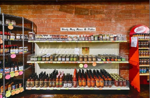 A shelf displaying various Bloody Mary mixes and pickles, with colorful labels and bottles in a store setting.