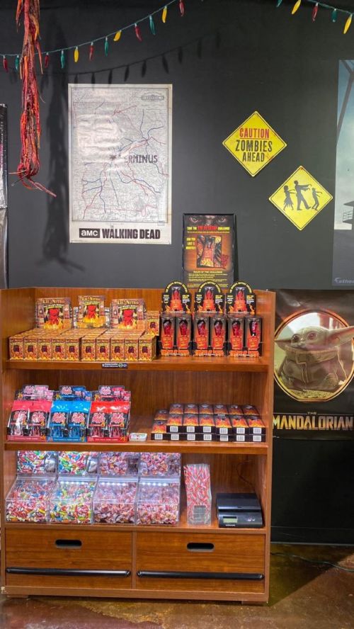 A wooden shelf displays various collectibles and candy, with themed posters and decorations on the wall behind it.