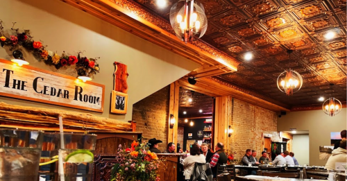 Cozy restaurant interior with wooden decor, warm lighting, and patrons enjoying their meals in a welcoming atmosphere.