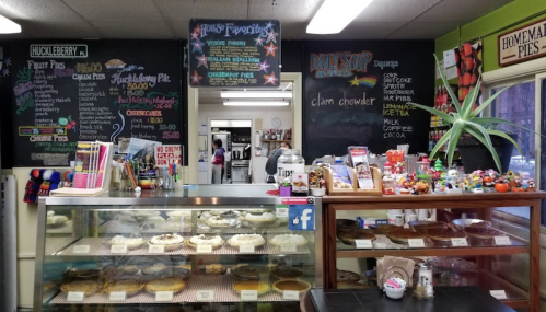 A cozy bakery display with various pies and desserts, chalkboard menus, and a welcoming atmosphere.