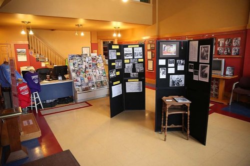 Interior of a museum or gallery featuring display panels, a reception area, and various historical photographs.