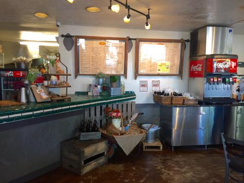 Cozy café interior with a green tiled counter, menu boards, drink dispensers, and rustic decor elements.