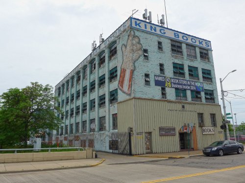 Abandoned building with faded "King Books" mural, antennas on roof, and a small bookstore entrance below.