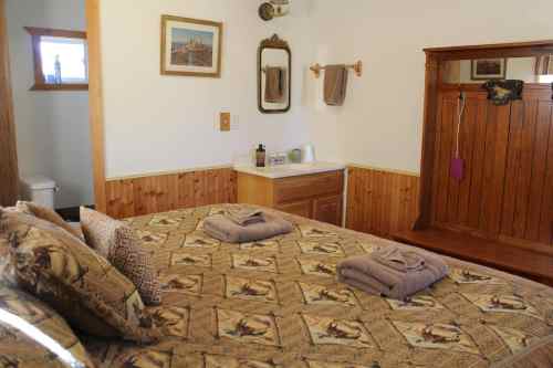 Cozy bedroom with a patterned bedspread, towels, and wooden furniture, featuring a mirror and a small sink area.