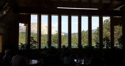 View from a restaurant with large windows, showcasing a mountain landscape and greenery outside.