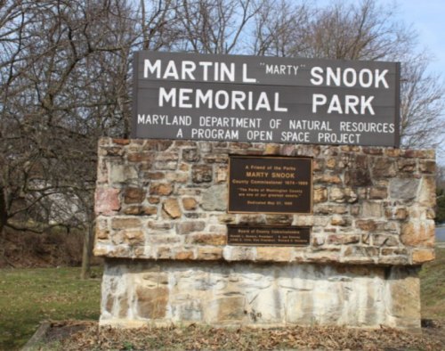 Sign for Martin L. Snook Memorial Park, featuring stone structure and trees in the background.