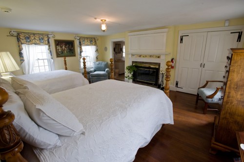 Cozy bedroom with two beds, a fireplace, and vintage decor, featuring soft lighting and warm colors.