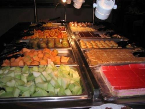 A buffet table filled with a variety of fresh fruits and colorful desserts, including cakes and jellies.
