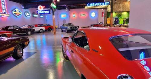 A vibrant car showroom featuring classic cars and colorful neon signs.