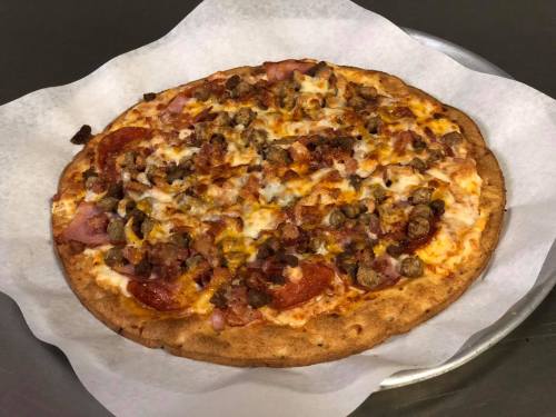 A freshly baked pizza topped with pepperoni, sausage, bacon, and melted cheese on a golden crust.