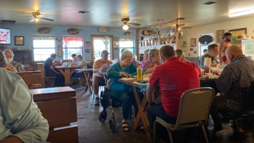 A busy restaurant interior with diners at tables, enjoying meals and chatting in a cozy atmosphere.