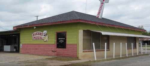 A colorful pizza restaurant with a green and pink exterior, featuring a sign that reads "Baker's Pizza."