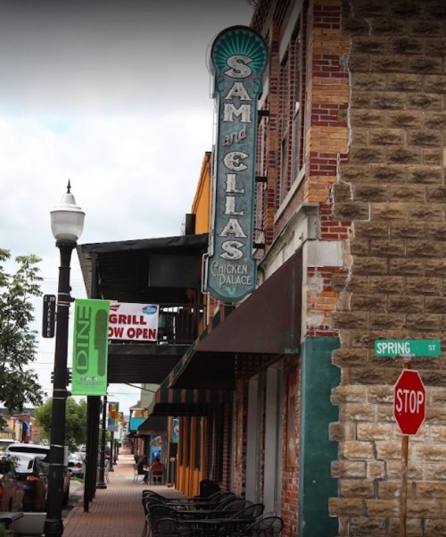 Street view featuring a restaurant sign for "Sam and Ella's Chicken Palace" and a stop sign on Spring Street.