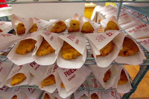 A display of fried coconut snacks wrapped in paper, arranged neatly on a wire rack.