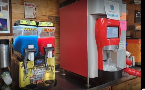 Two beverage dispensers: one with blue raspberry and wild strawberry slushies, and another for blueberry drinks.