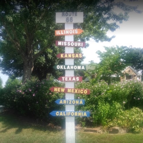 Signpost for Route 66 with directional arrows pointing to states: Illinois, Missouri, Kansas, Oklahoma, Texas, New Mexico, Arizona, California.