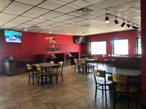 Interior of a pizza restaurant with red brick walls, tables, and TVs on the wall. Bright and spacious atmosphere.